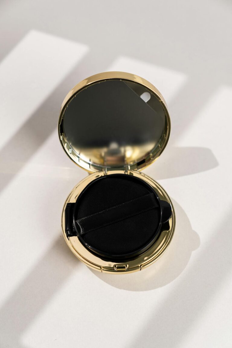A stylish golden compact with a mirror casting elegant shadows in sunlight.
