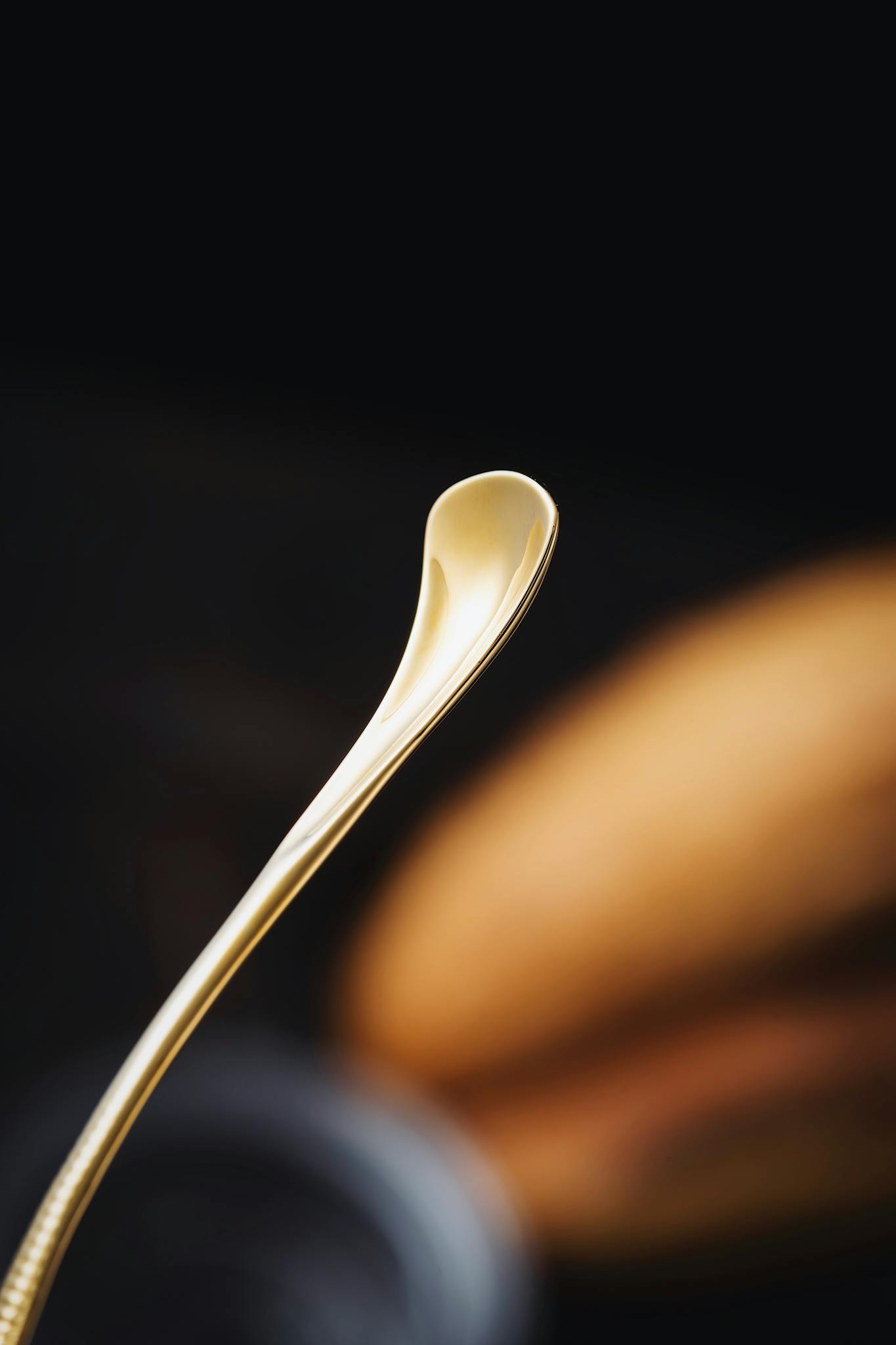 Close-up of a stylish golden spoon with a black background, capturing the essence of luxury kitchenware.